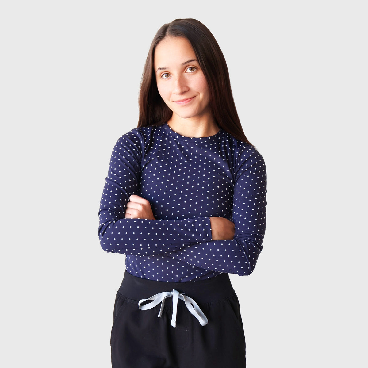 Navy & White PolkaDot CoreSupport Underscrub on a model with arms crossed: long-sleeve navy top with small white polka dots